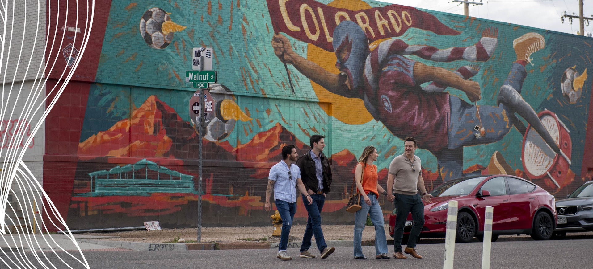 Four people walking in front of a mural in Downtown Denver